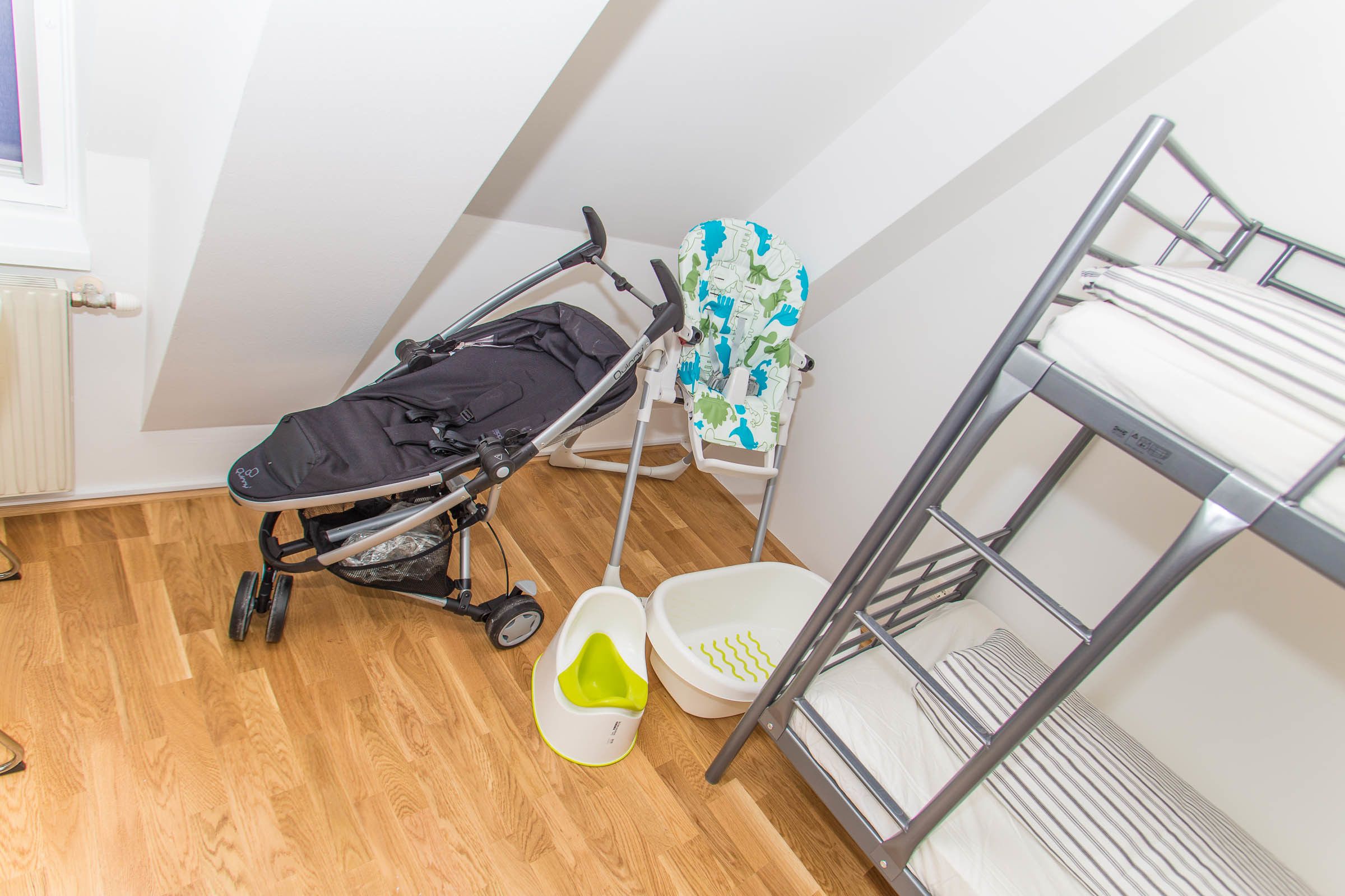 Una habitación con literas, un cochecito de bebé, un cambiador para bebés y un radiador.