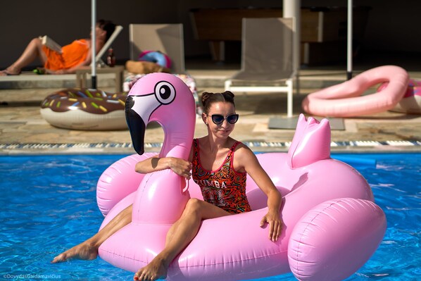 A person in a pink flamingo float in a swimming pool. - Fardini Seaside Hotel (Corfu)