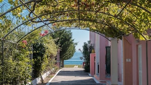 A pathway leading to a building with a view of the sea. - Fardini Seaside Hotel (Corfu)
