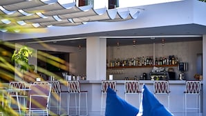 A bar area with multiple seating options and a variety of bottles on the shelves. - Fardini Seaside Hotel (Corfu)