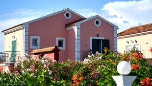 A pink building with a red door, white windows, and a small balcony with a railing. - Fardini Seaside Hotel (Corfu)