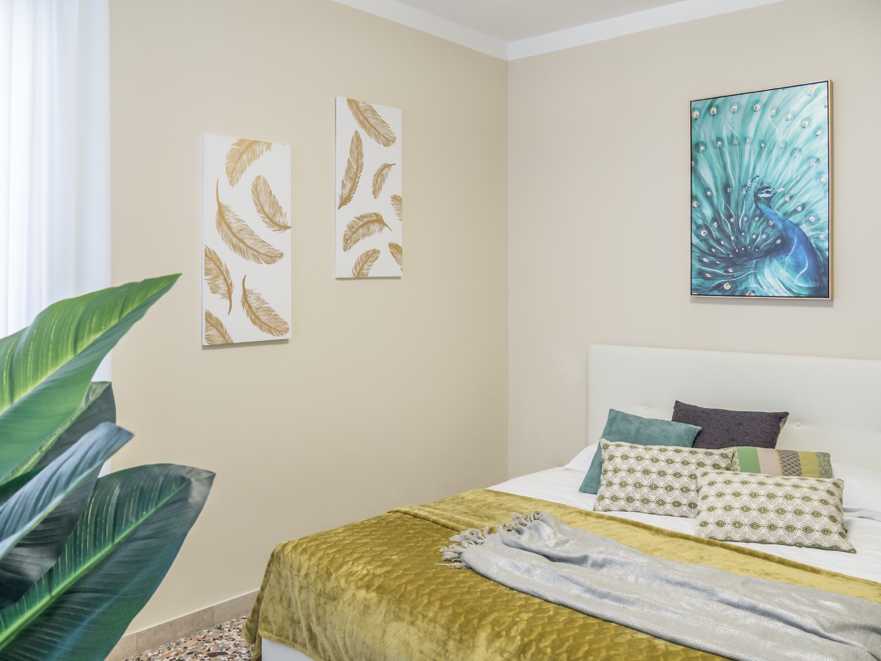A bedroom with a bed, pillows, a blanket, and two wall art pieces.