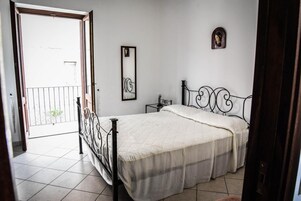 A bedroom with a bed, a nightstand, a mirror, and a small wall decoration.