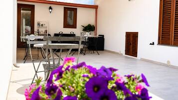 Una veranda esterna con zona pranzo, una porta in legno e un punto luce fissato al muro.