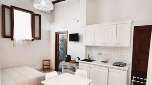 Una cocina compacta con armarios blancos, una mesa de comedor con sillas, una lámpara colgante y piso con diseño.