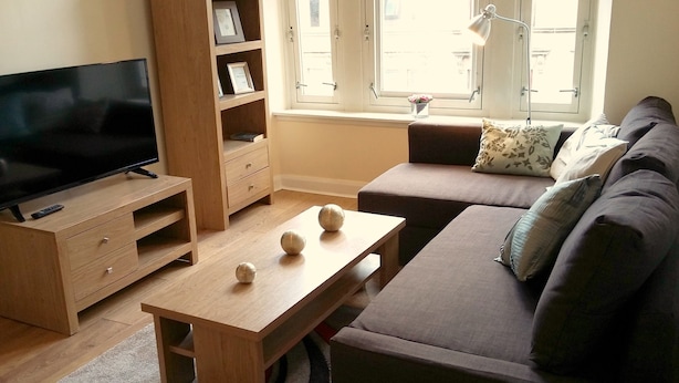 Un salon doté d’un téléviseur à écran plat, de meubles en bois, d’un canapé et d’une fenêtre offrant une vue agréable.