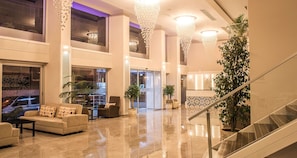A spacious lobby with a high ceiling, large windows, and a staircase. - Cimenoglu Hotel (Denizli)