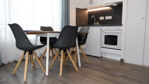 Een moderne keuken met een eettafel en stoelen, witte kasten en een inbouwoven.