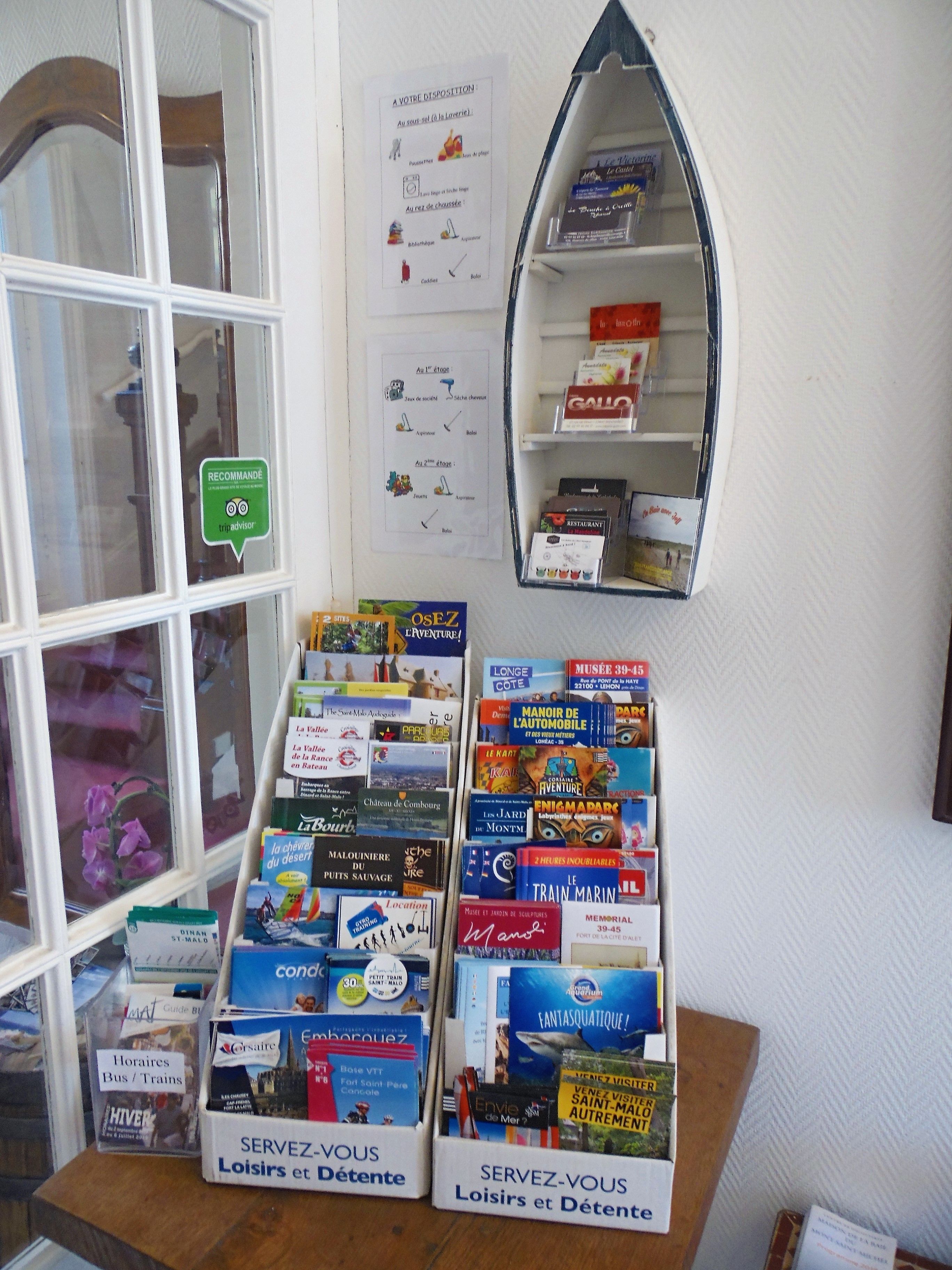 Exhibición de libros y folletos de viajes en una librería, con una ventana y una estantería al fondo.