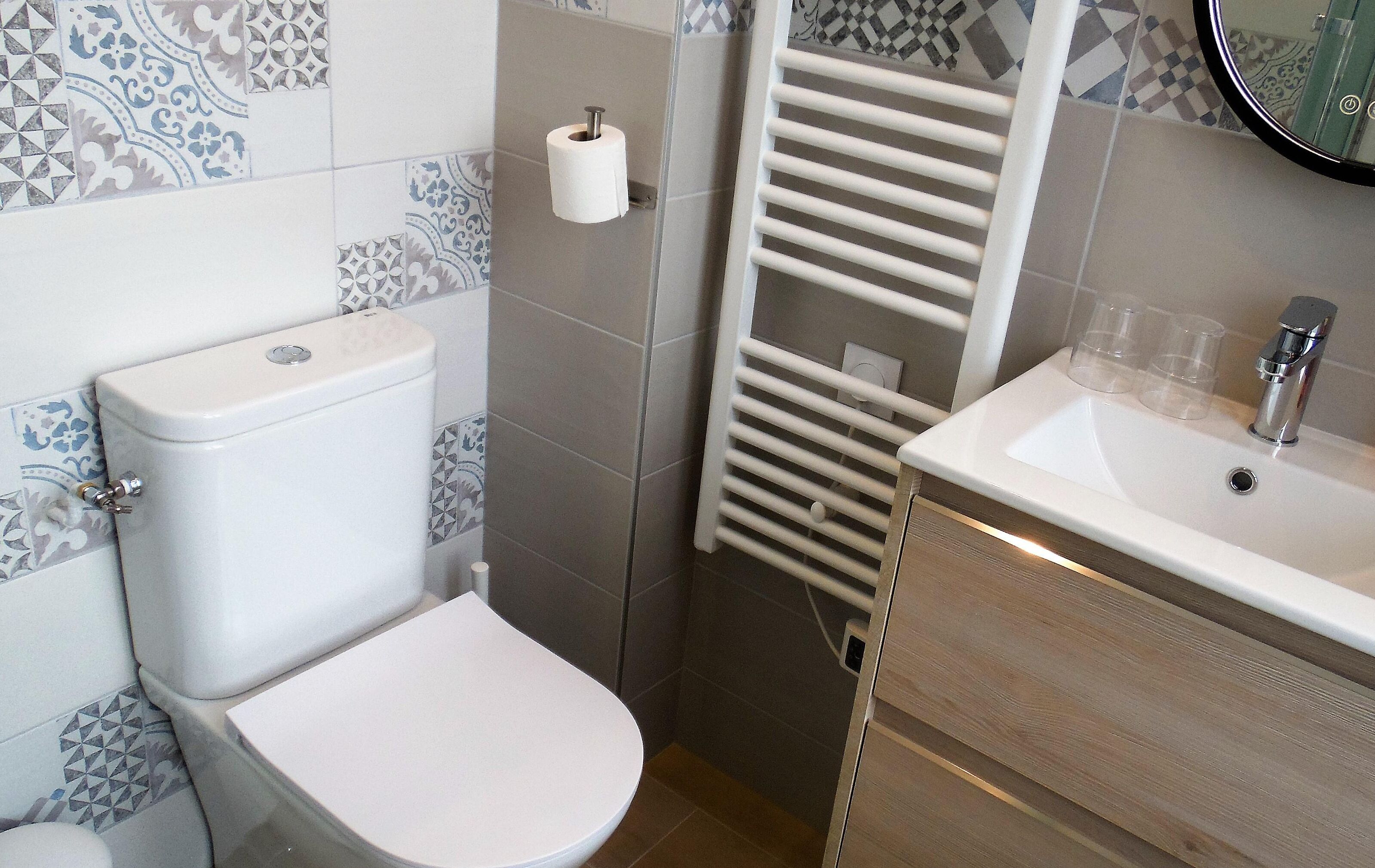 Une salle de bain équipée de toilettes, d’un lavabo et d’un porte-serviettes.
