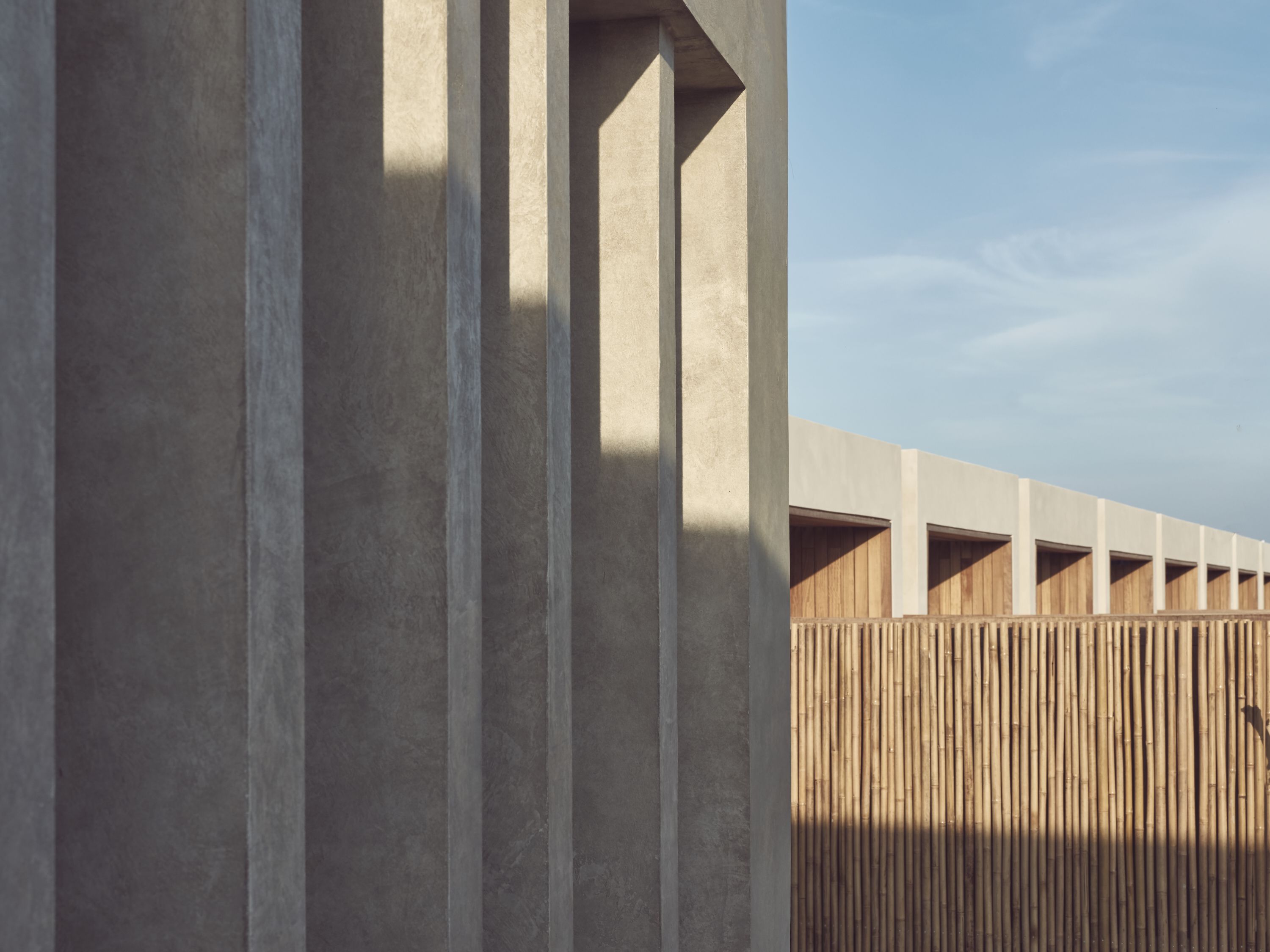 A modern building with vertical concrete columns and wooden slats.