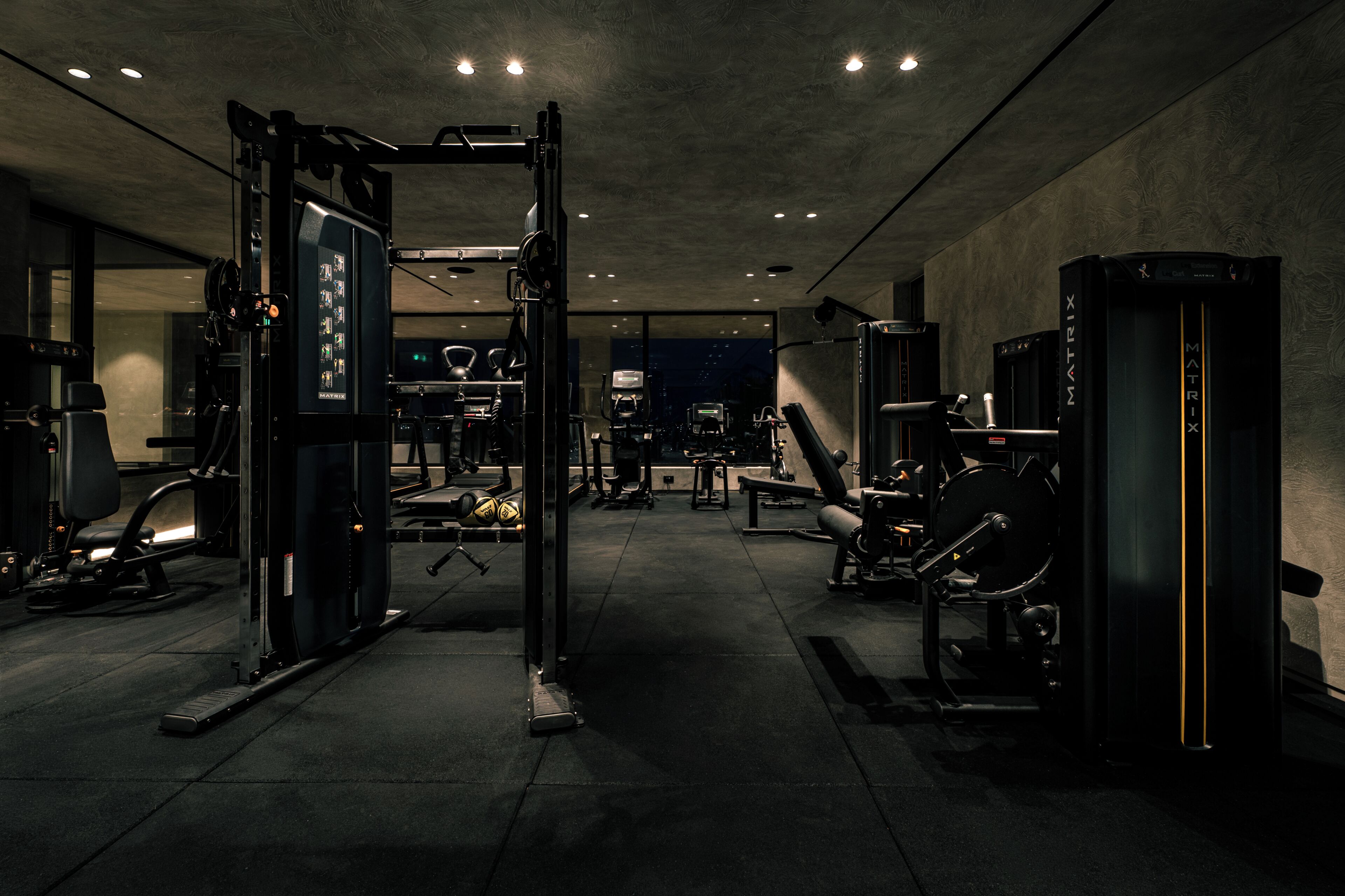 A gym with various exercise equipment, including a squat rack, benches, and weight machines.