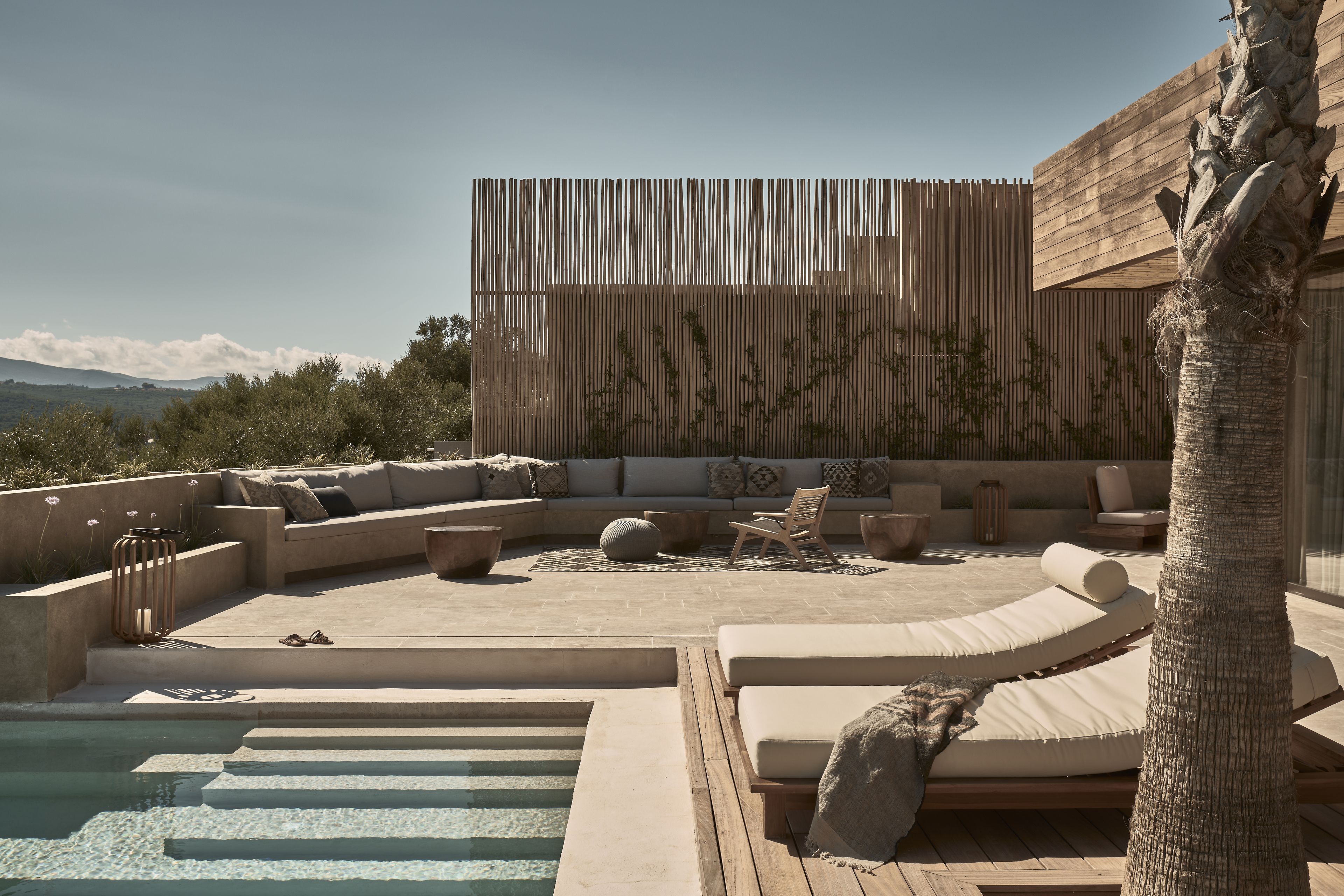A rooftop pool area with a wooden deck, lounge chairs, and a modern wooden wall.