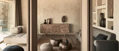 Una sala moderna con sofá, reposapiés y un mueble con objetos decorativos.