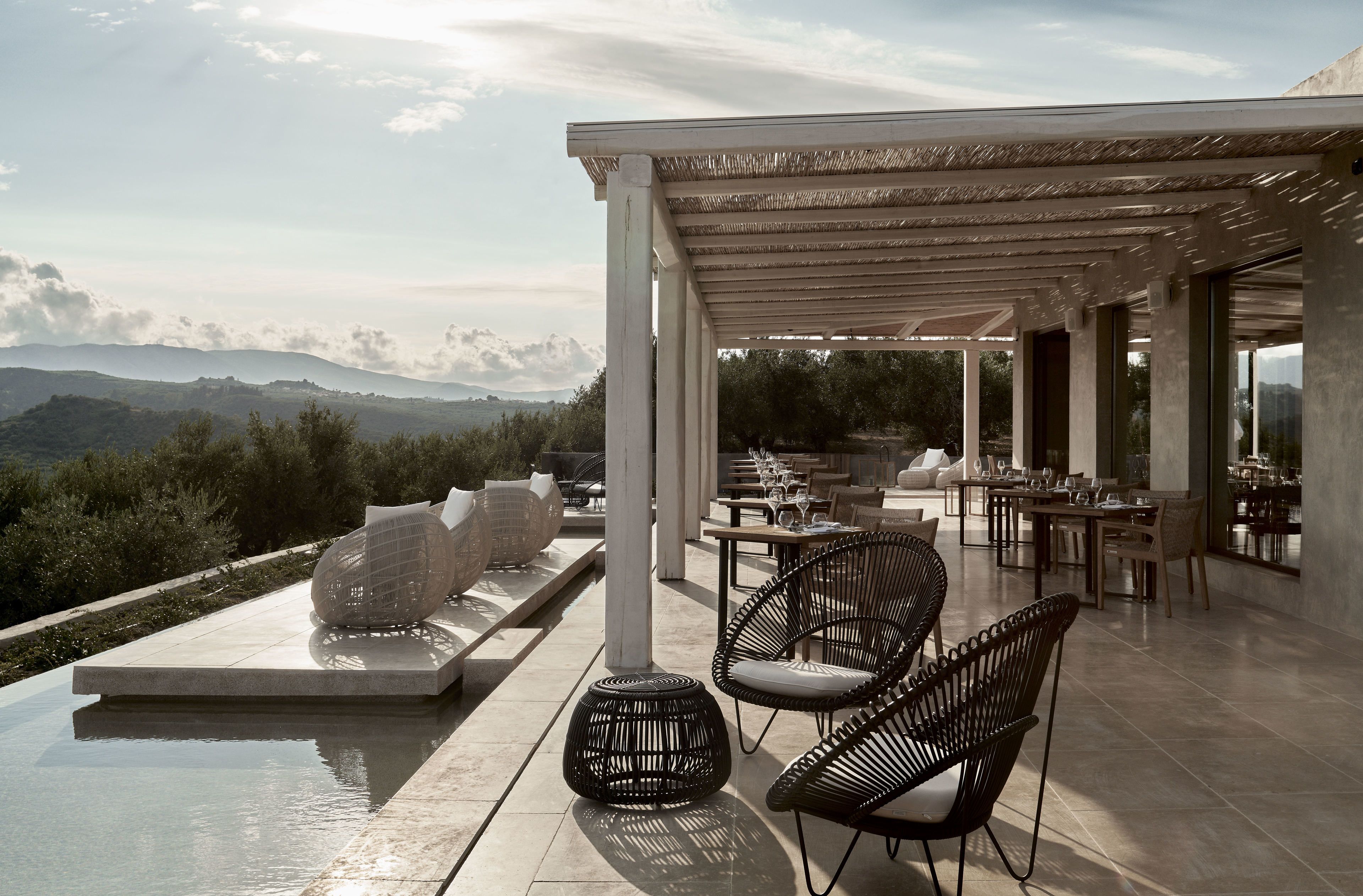 Un espace extérieur aménagé pour les repas, avec des meubles en rotin de style moderne, une piscine et une vue sur les montagnes.