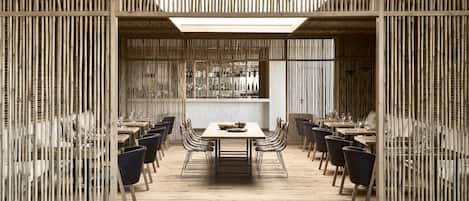 A modern dining area with bamboo partitions, wooden tables, and black chairs.