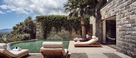 A poolside area with lounge chairs and a stone wall.