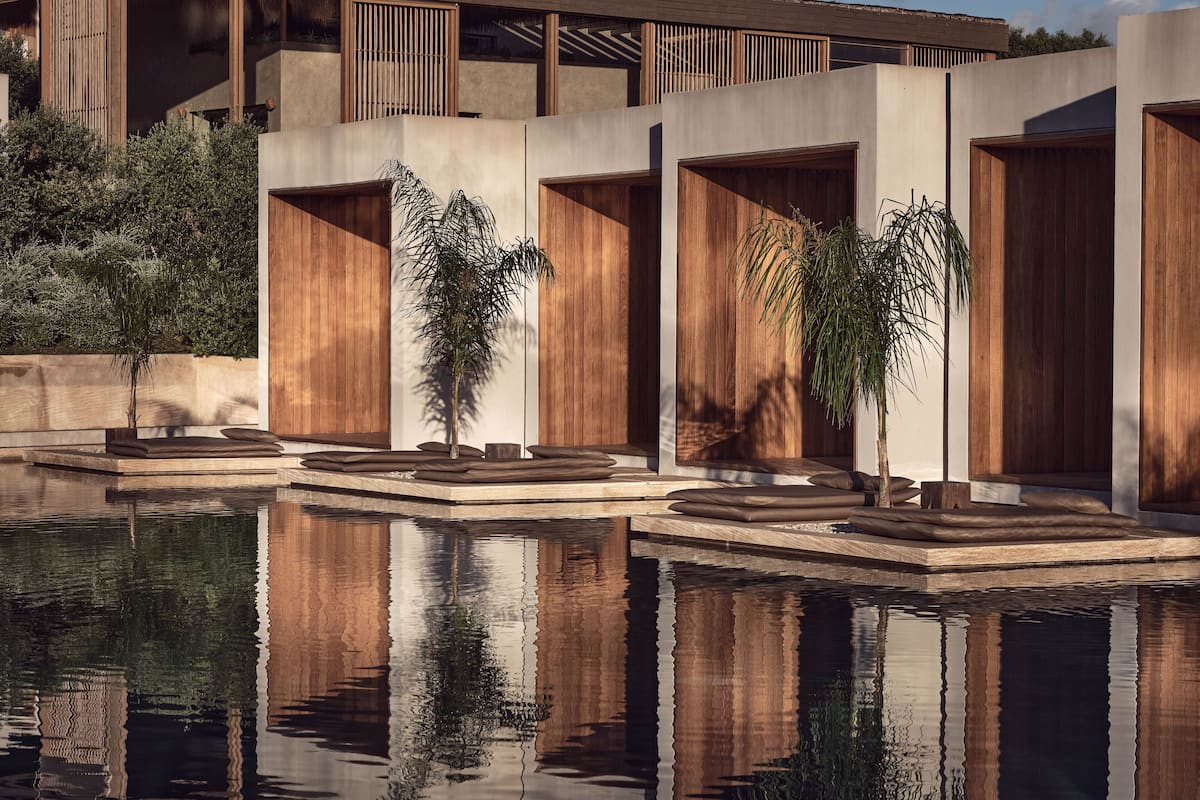 A modern pool area with wooden deck seating and a reflection in the water.