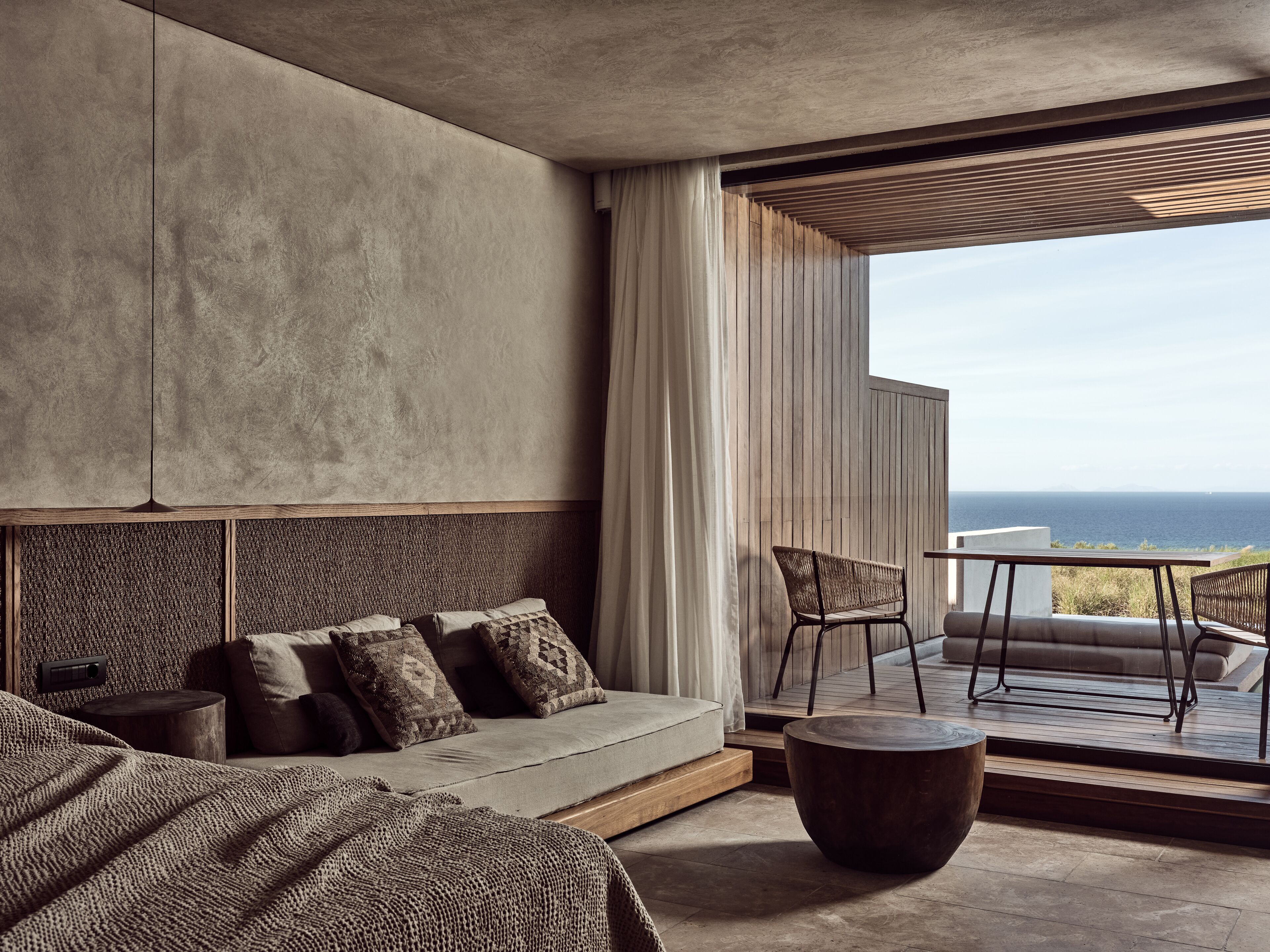 Une chambre moderne avec un grand lit, un canapé et une vue sur l’océan.