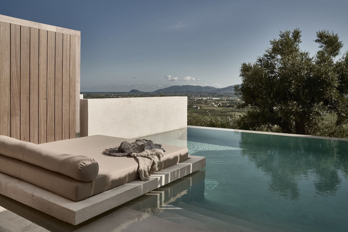 A modern outdoor seating area with a pool, overlooking a scenic landscape.