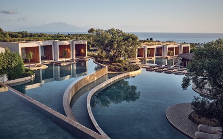 A resort with infinity pools, wooden cabins, and a view of the sea.