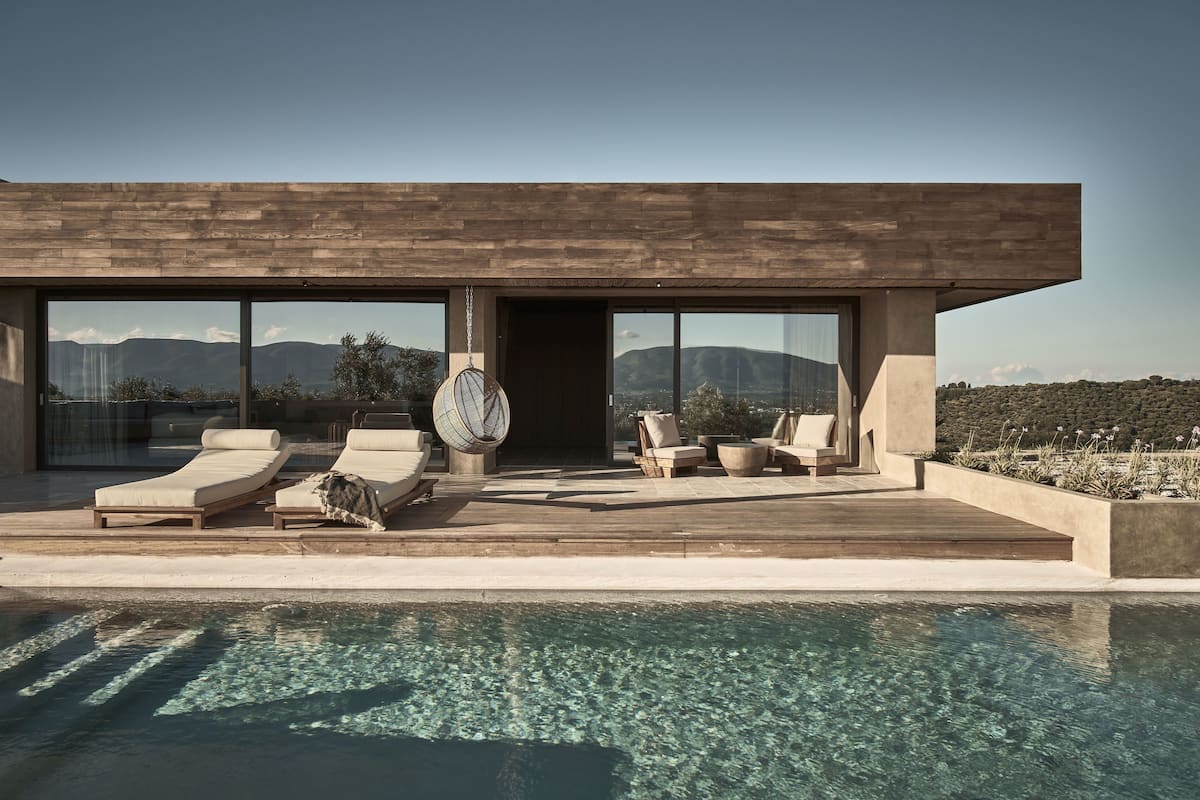 A modern house with a pool, large windows, and outdoor seating.