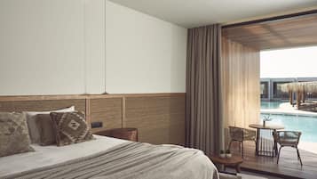Een moderne hotelkamer met een groot bed, uitzicht op een zwembad en een balkon met zitplaatsen.