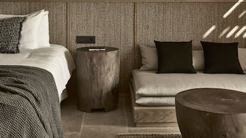 Un dormitorio moderno con una cama, dos mesitas de noche, un banco y una pared con textura.