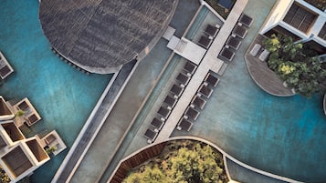 Vista aérea de un hotel moderno con piscina central, zonas de estar al aire libre y un jardín ajardinado.