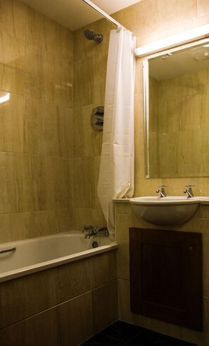 A bathroom with a bathtub, a sink, and a shower curtain.