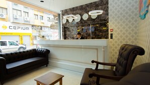A reception area with a sofa, armchair, and a wooden table. - Hotel Iz (Izmir)