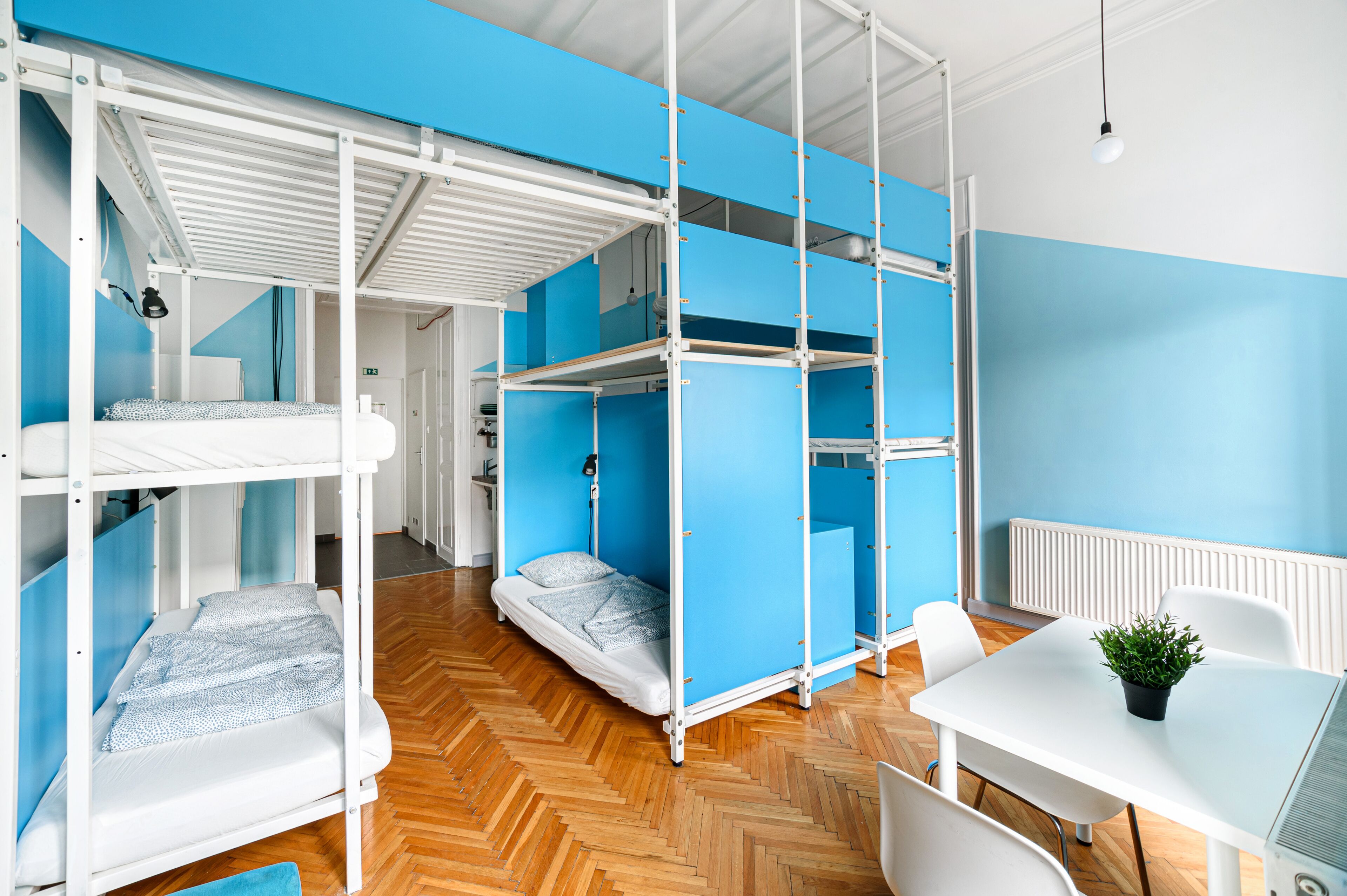 Ein Zimmer mit Stockbetten, einem Tisch mit Pflanze und einem Heizkörper.