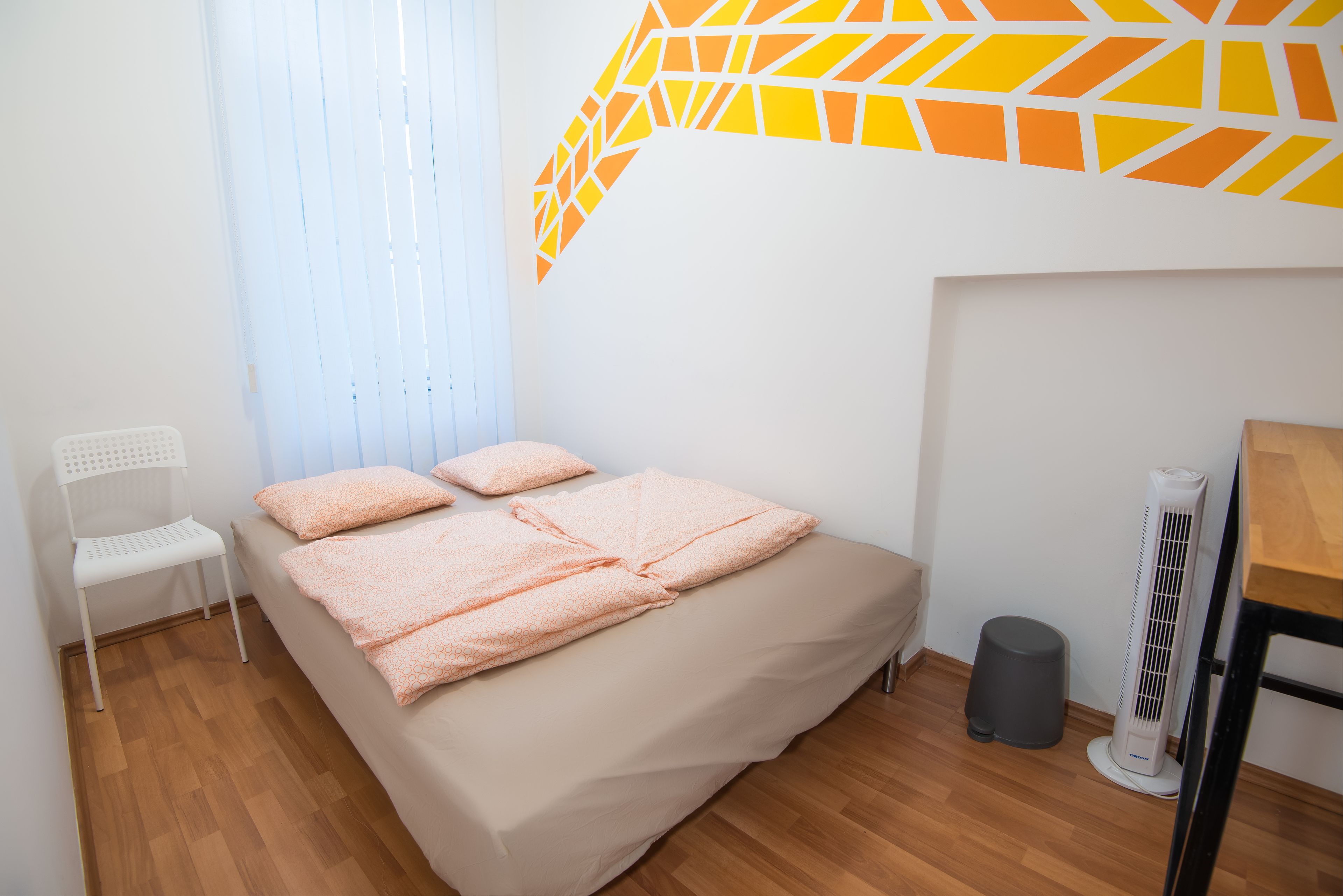A bedroom with a bed, a chair, a waste bin, and a heater.