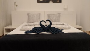 A neatly made bed with patterned pillows and a heart-shaped towel arrangement. - Avenue Hostel (Budapest)