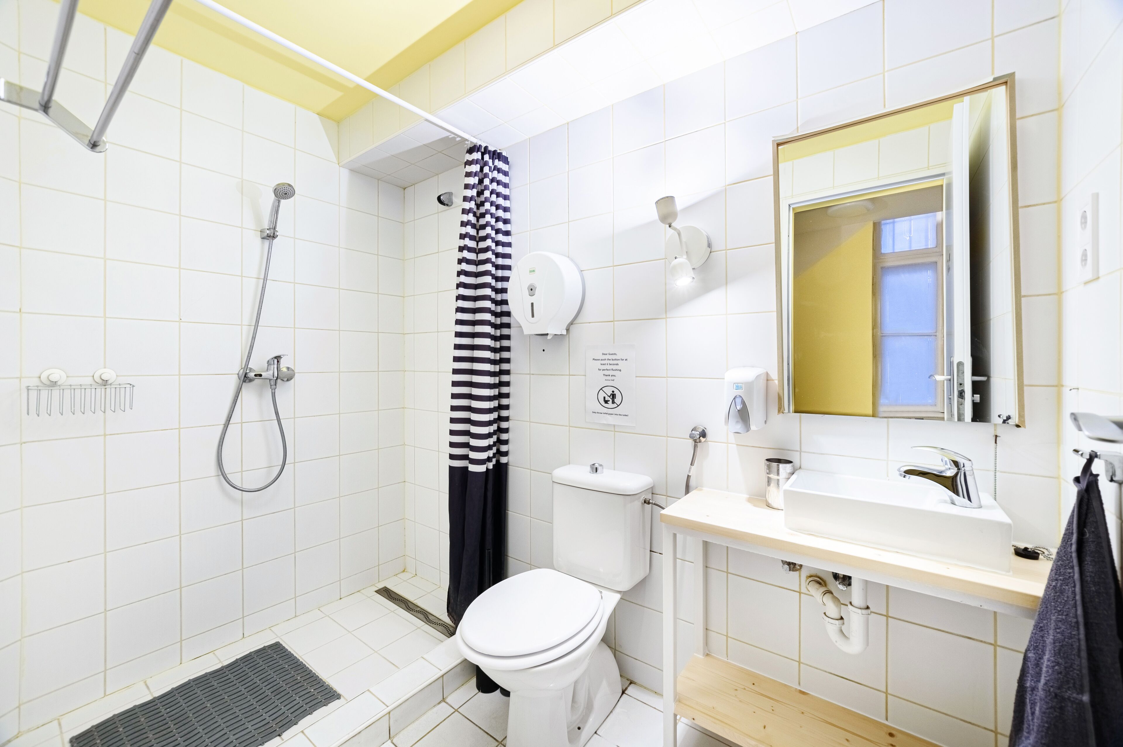 A bathroom with a shower, toilet, sink, and a mirror.