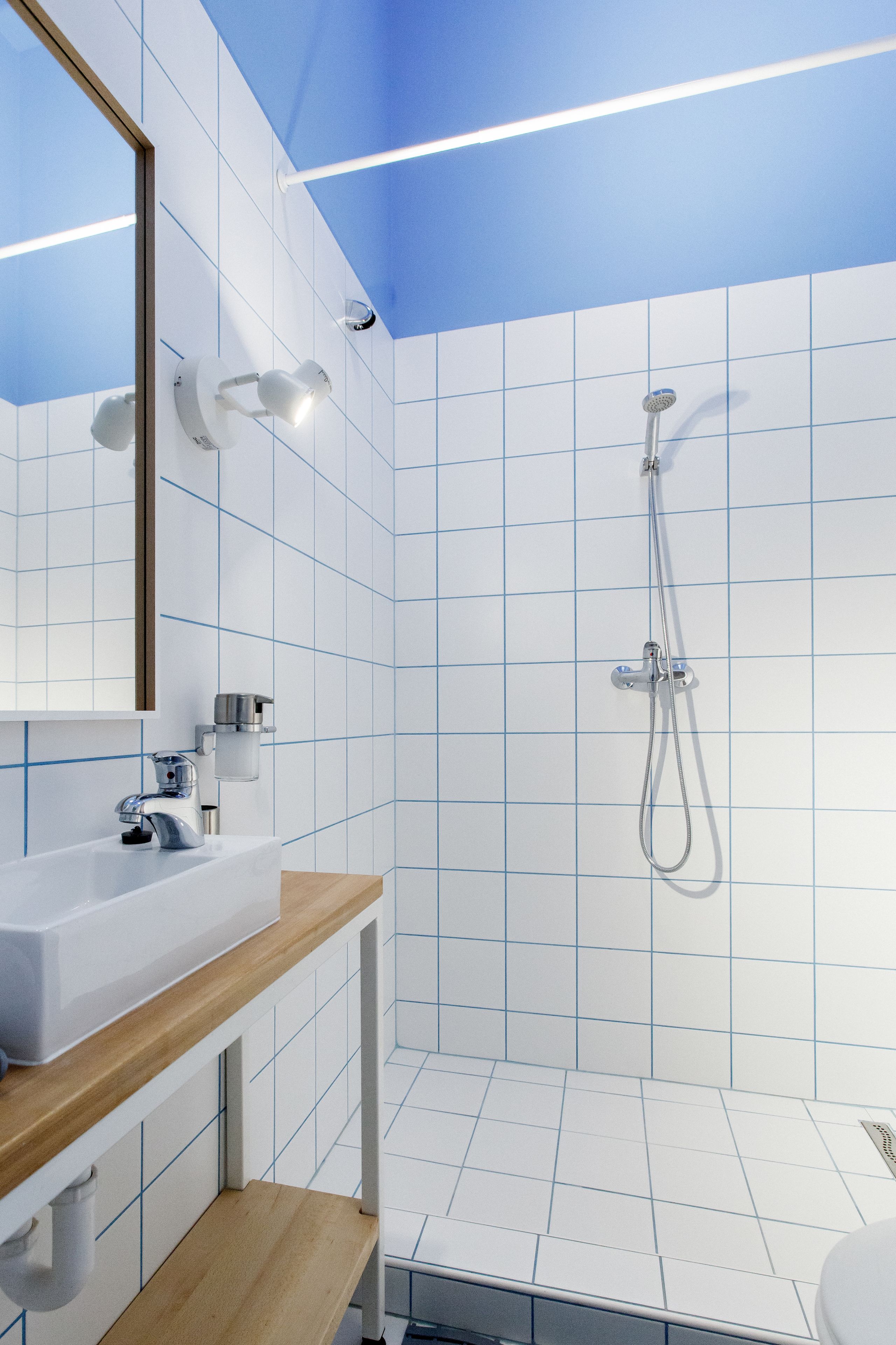 A modern bathroom with a white sink, wooden countertop, and a glass shower enclosure.