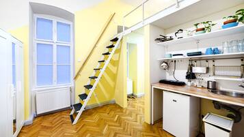 Una cocina compacta con piso de espiga, un refrigerador blanco, un lavamanos y una ventana.