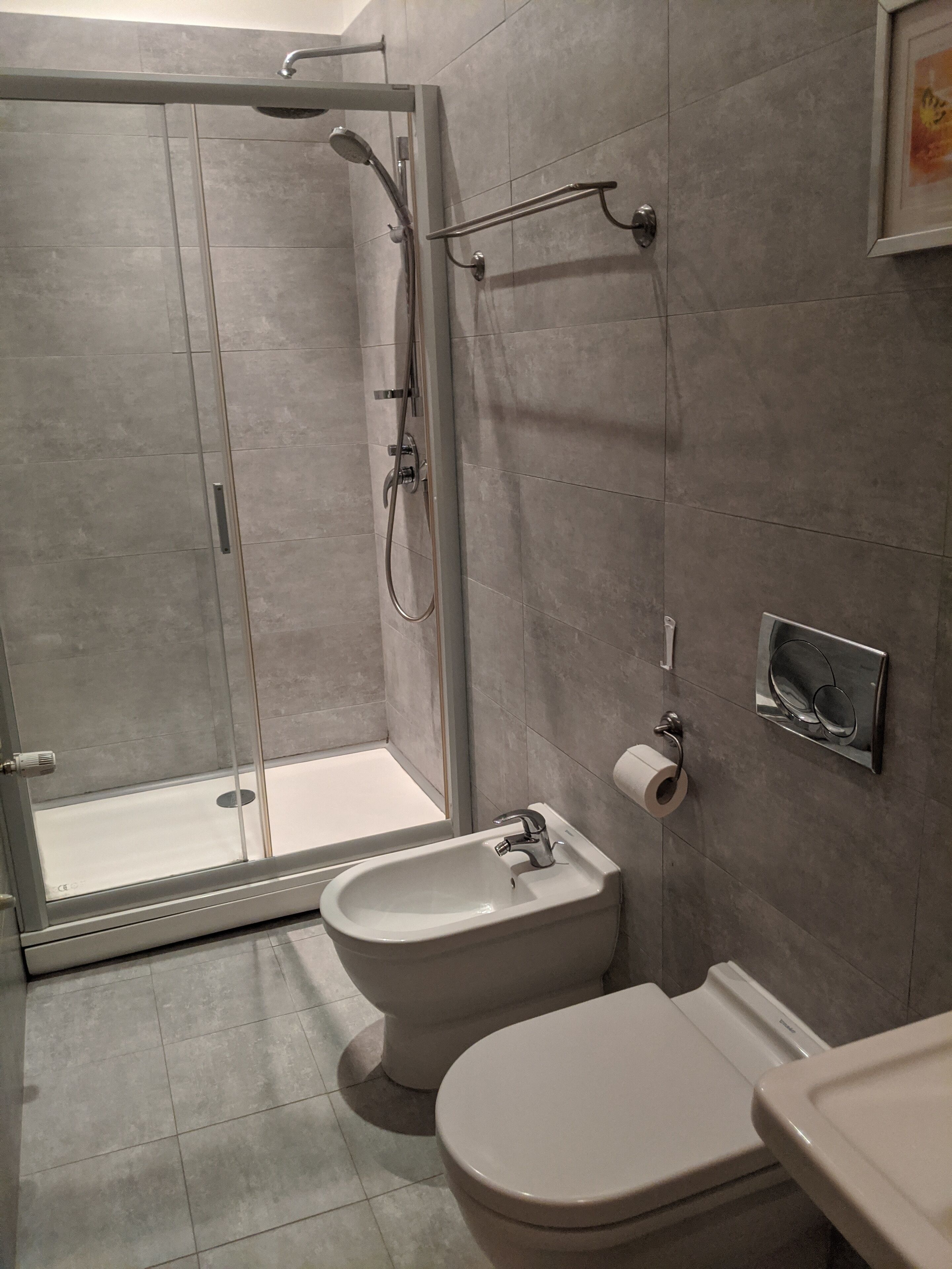 A modern bathroom with a glass-enclosed shower, a bidet, a toilet, and a sink.