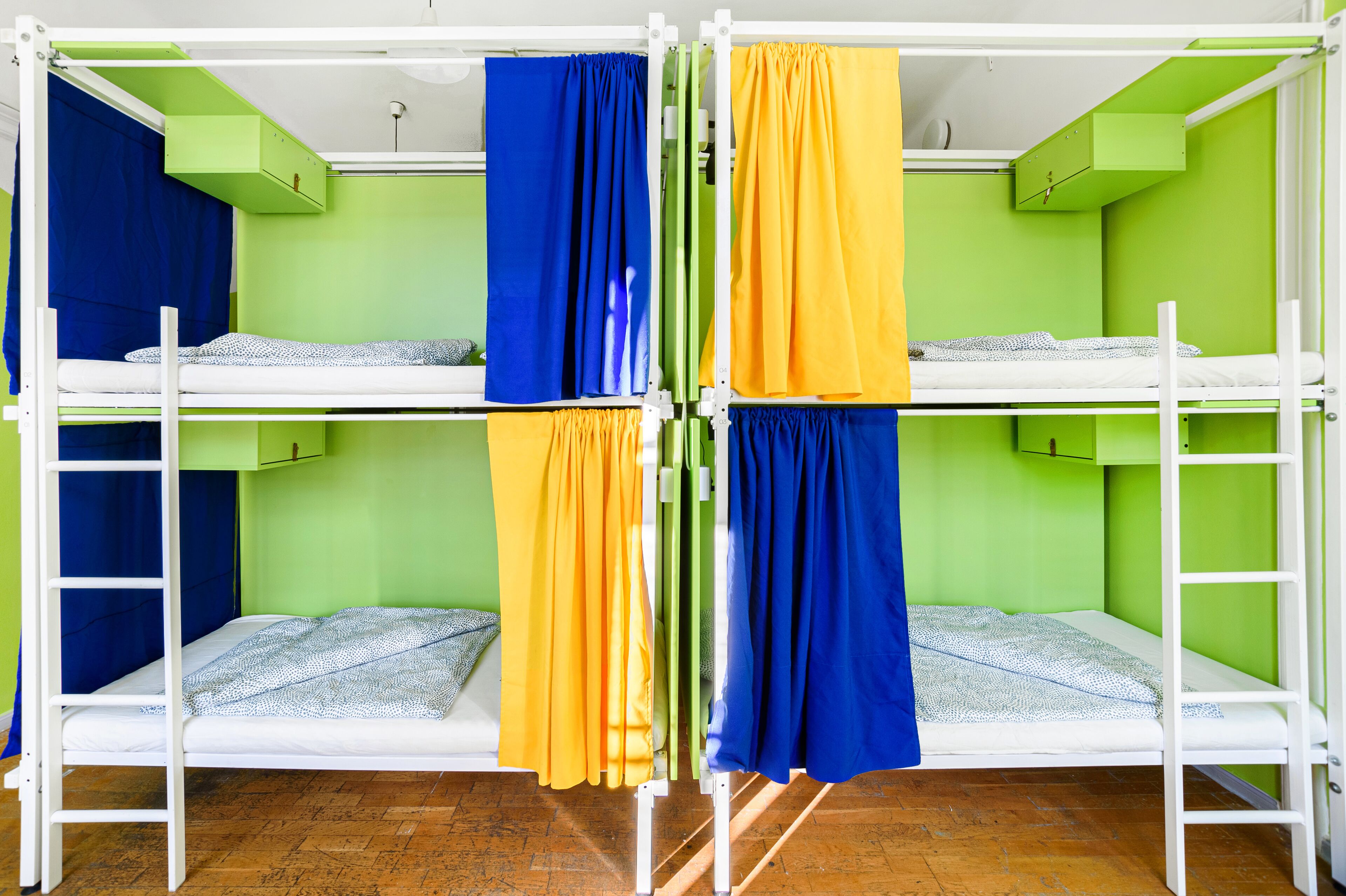 A bunk bed room with green walls and white railings.