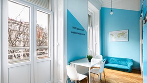 A modern room with a white table and chairs, a blue sofa, and a world map on the wall. - Avenue Hostel (Budapest)