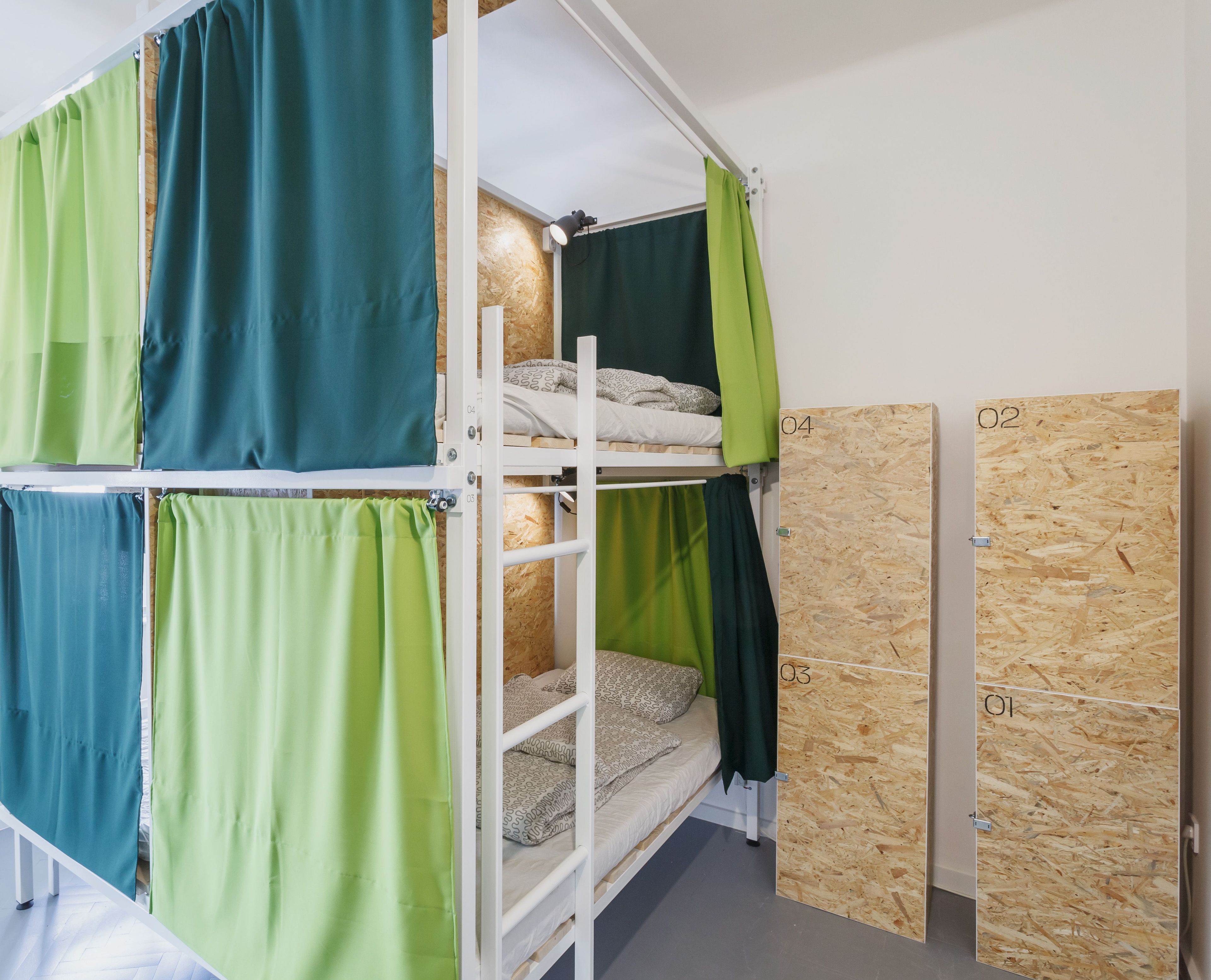 A bunk bed with green curtains, a wooden wall panel, and a white ceiling.
