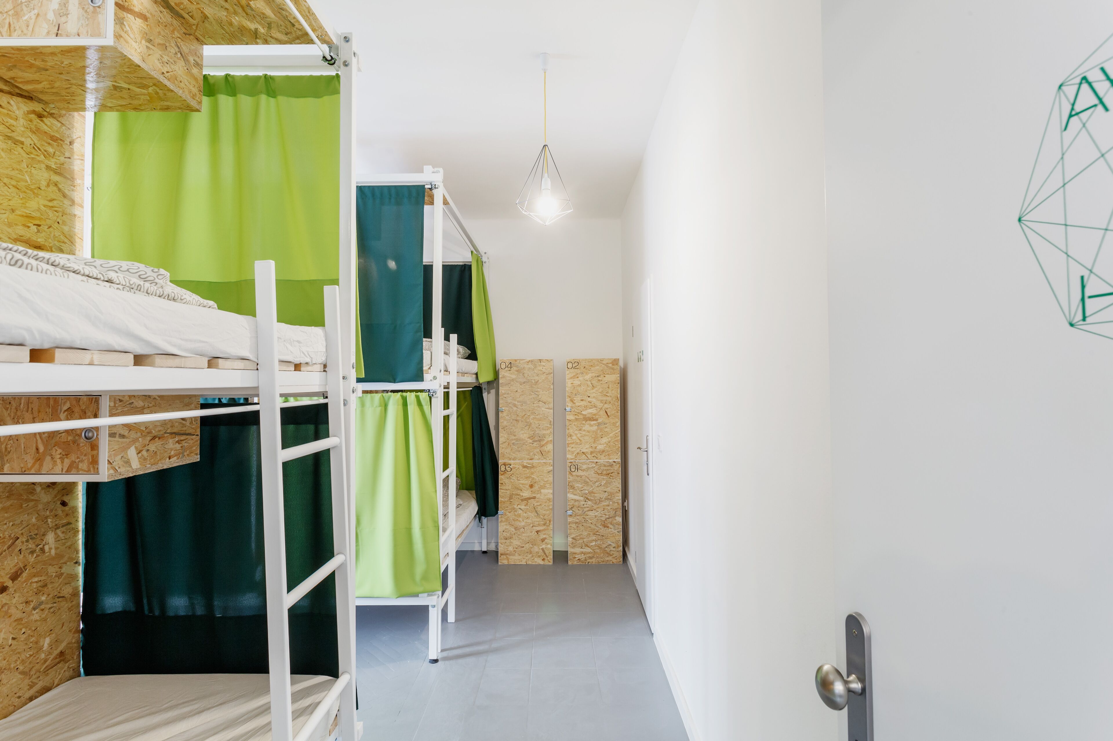 A bunk bed room with a wooden headboard, a green curtain, and a geometric wall decoration.