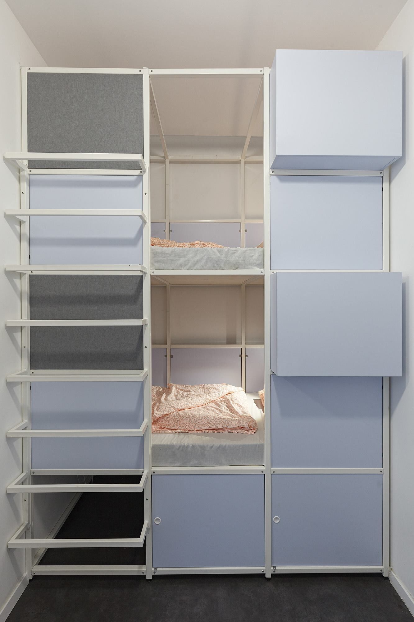 Un módulo de almacenamiento compacto con varios estantes y compartimentos, que incluye una zona con cama.