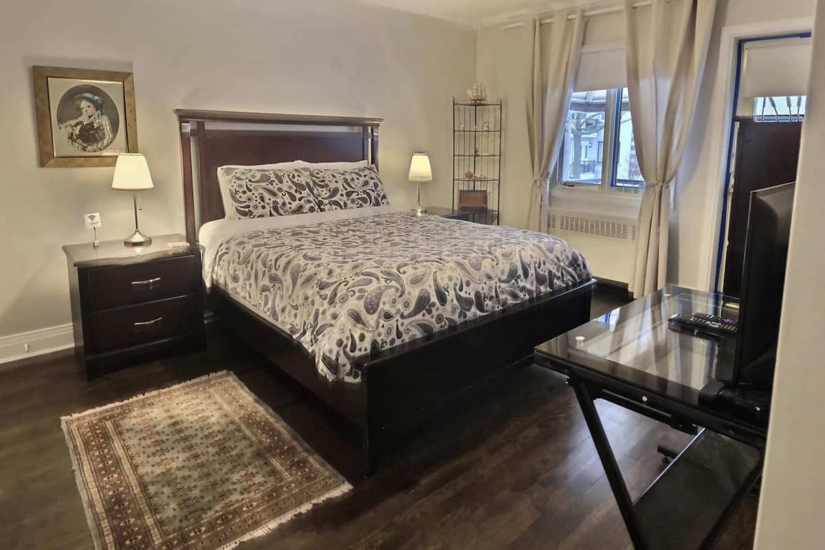 Un dormitorio con cama, mesitas de noche, un escritorio y una silla.