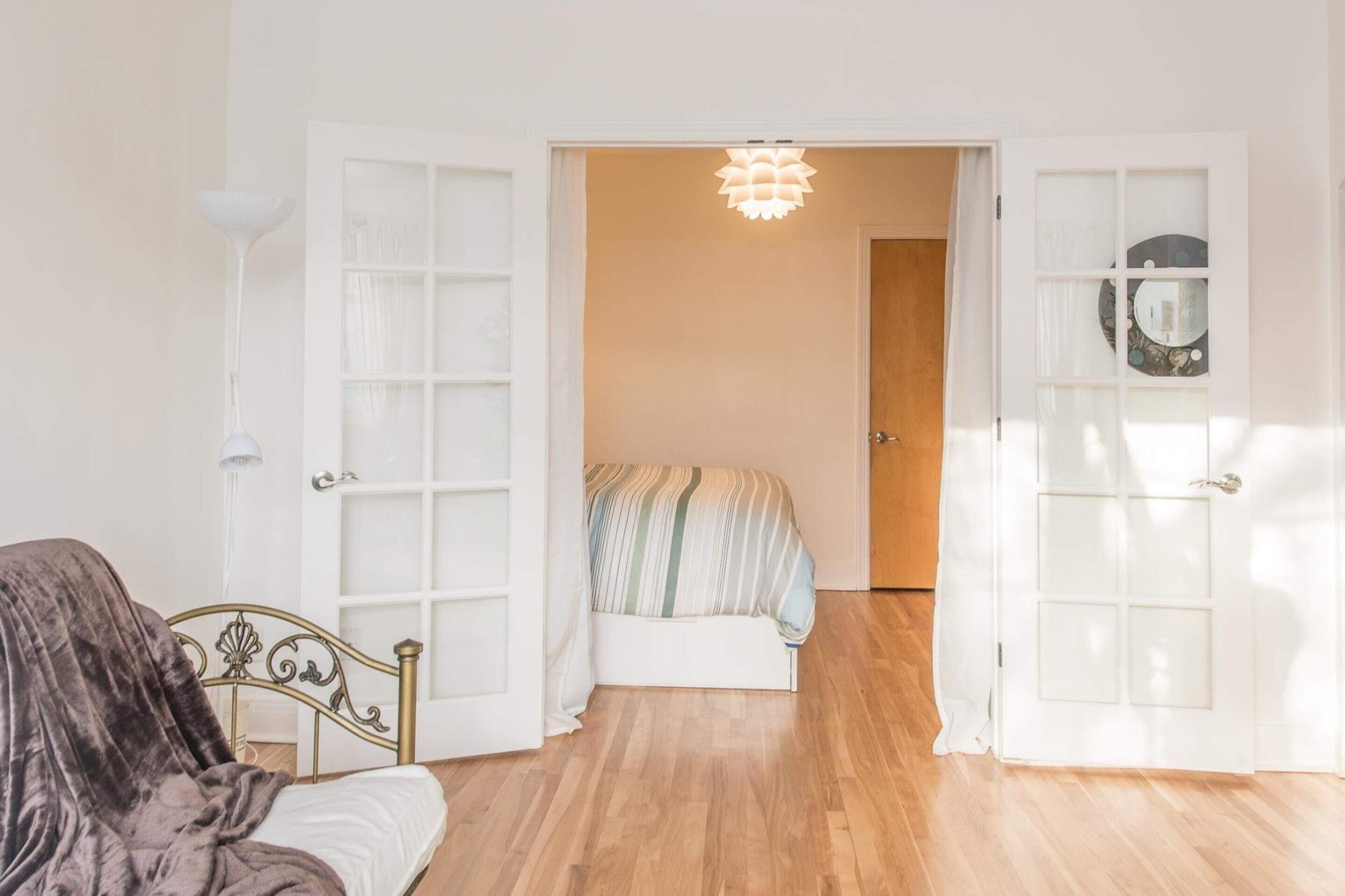 A bedroom with a bed, a wardrobe, and a door leading to another room.