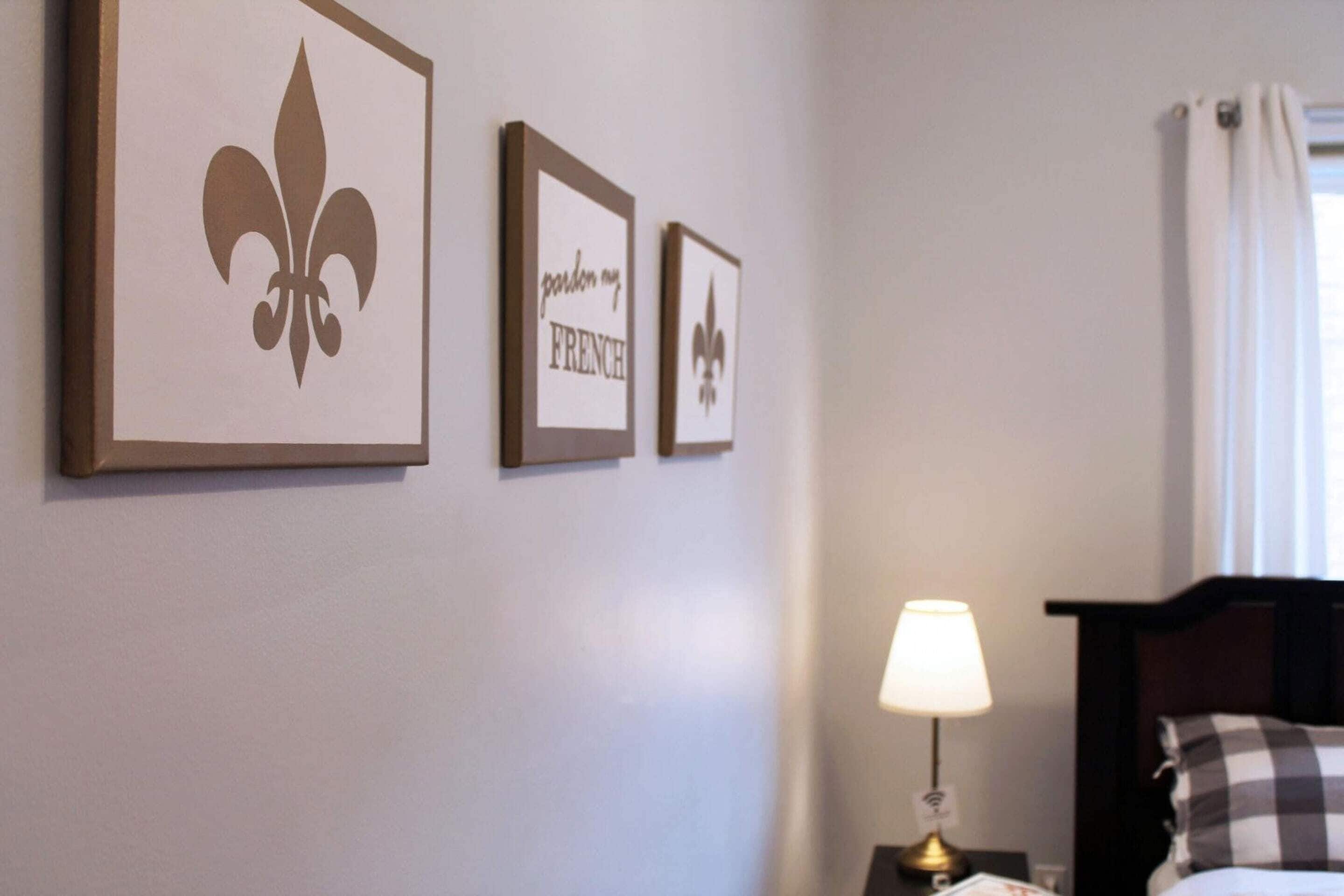 A hotel room with a bed, a nightstand with a lamp, and three framed pictures on the wall.