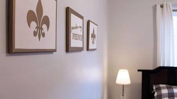 A hotel room with a bed, a nightstand with a lamp, and three framed pictures on the wall.