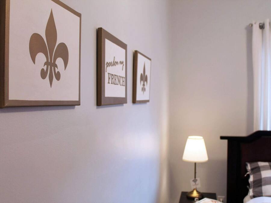 A hotel room with a bed, a nightstand with a lamp, and three framed pictures on the wall.