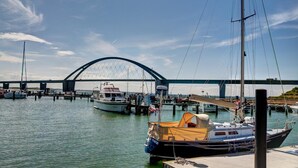 A marina with boats docked, a bridge in the background, and a clear sky. - Hotel Sonneninsel Fehmarn (Fehmarn)