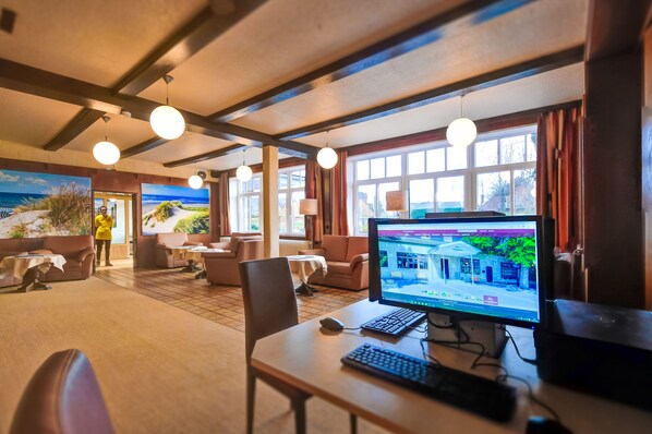 A room with a wooden ceiling, round pendant lights, a large window with curtains, a computer on a desk, and a view of the outdoors. - Hotel Sonneninsel Fehmarn (Fehmarn)